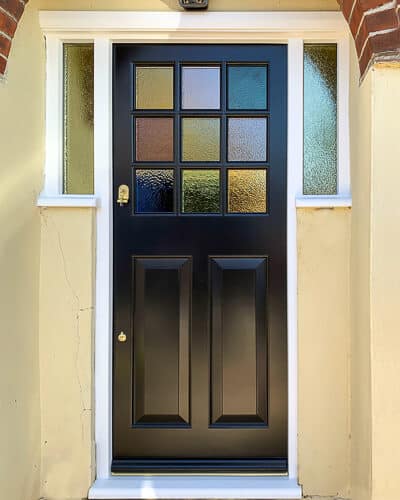 Coloured glass 1930s door. 9 light 1930s door with every pane a different coloured glass. Door is painted black and wing window frame has coloured glass too. Door frame is painted white