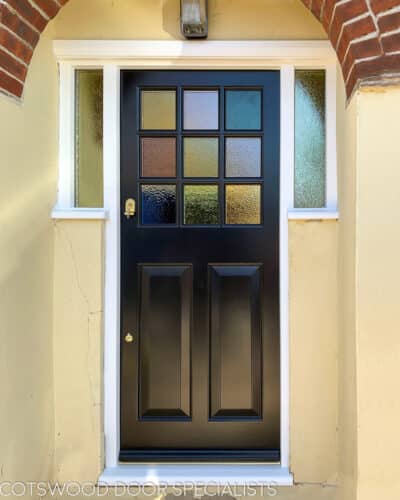 Coloured glass 1930s door. 9 light 1930s door with every pane a different coloured glass. Door is painted black and wing window frame has coloured glass too. Door frame is painted white