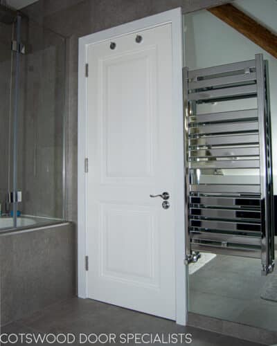 Contemporary bathroom door. Door has 2 decorative bold raised panels. Polished chrome door handles