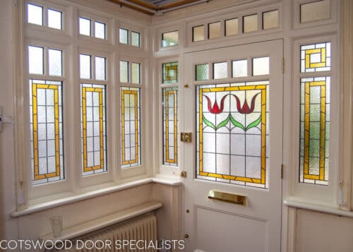 Edwardian casement window. Large Edwardian casement window incorporated into a front entrance doorway. Decorative wooden glazing bars dividing window into multiple panes. Stained glass to window. All double glazed. White painted wooden window. Interior hall shot showing off stained glass