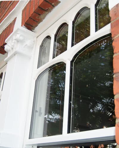 Edwardian sash window. Decorative Edwardian sash window with multiple shaped panes of glass. Glazing is a double glazed. Wooden window is painted white and fitted into a red brick London home