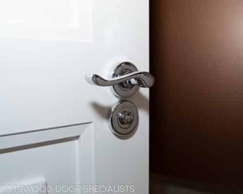 En Suite Contemporary door. White painted bespoke internal door to ensuite with polished chrome door furniture. Closeup of handle
