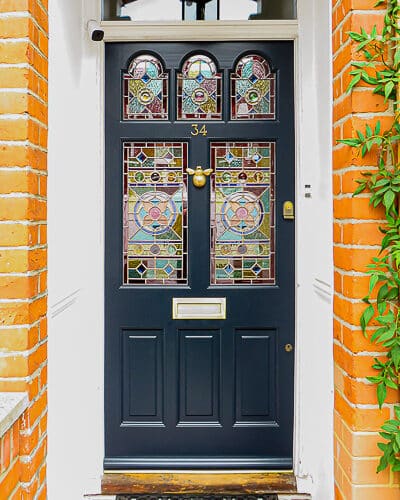 Five light Victorian door . Victorian front door with 5 pieces of geometric stained glass. Door has brass door furniture and is fitted with a bee door knocker. front door fitted into london home of brick