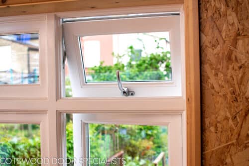Flush casement window. Traditional white painted wooden flush casement window. Window is fitted into a reclaimed brick home garden office London. Picture shows window from inside