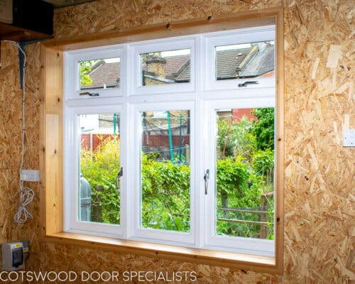 Flush casement window. Traditional white painted wooden flush casement window. Window is fitted into a reclaimed brick home garden office London. Picture shows window from inside
