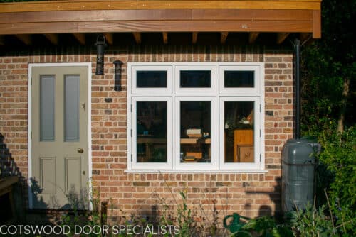 Flush casement window. Traditional white painted wooden flush casement window. Window is fitted into a reclaimed brick home garden office London. Picture shows window from garden.