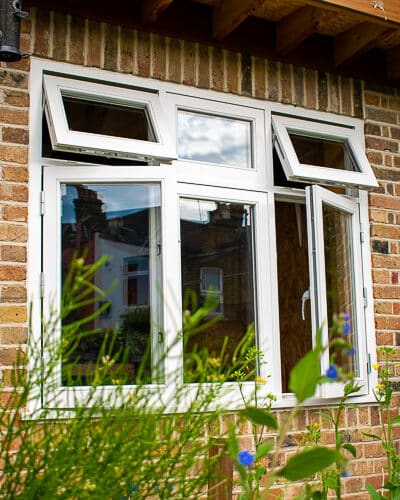 Flush casement window. Traditional white painted wooden flush casement window. Window is fitted into a reclaimed brick home garden office London. Picture shows window from garden. Window has double glazed clear glass