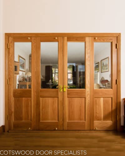 Oak bifolding doors dividing 2 rooms. Clear glass in doors to let light though. Doors have clear finish on them to show off the grain.