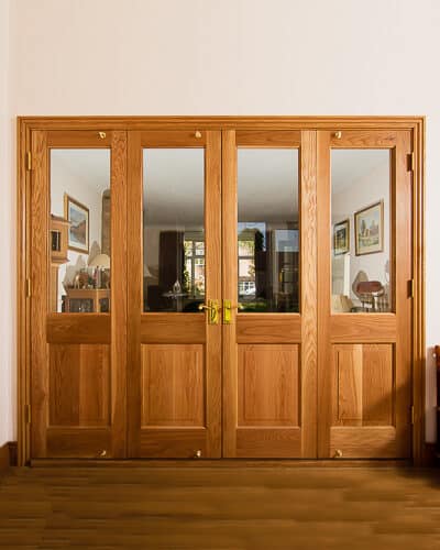 Oak bifolding doors dividing 2 rooms. Clear glass in doors to let light though. Doors have clear finish on them to show off the grain.