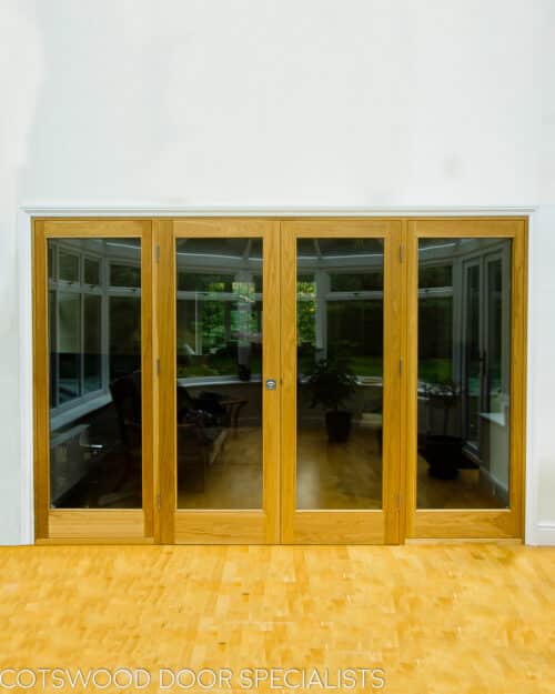 Oak glazed room divider. Fully glazed oak door and frame. Doors fold back fully onto door frame. Doors divide living room and conservatory