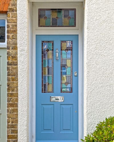 Opening fanlight Victorian door. Victorian front door with stained glass, door painted light blue. Door frame has an opening fanlight. Geometric stained glass design