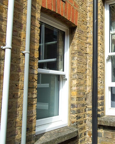 Simple box sash window. 1 over 1 box sash window. Window is fitted into london home with yellow stock bricks. The window has an etched bottom pane for privacy as it is installed into a bathroom