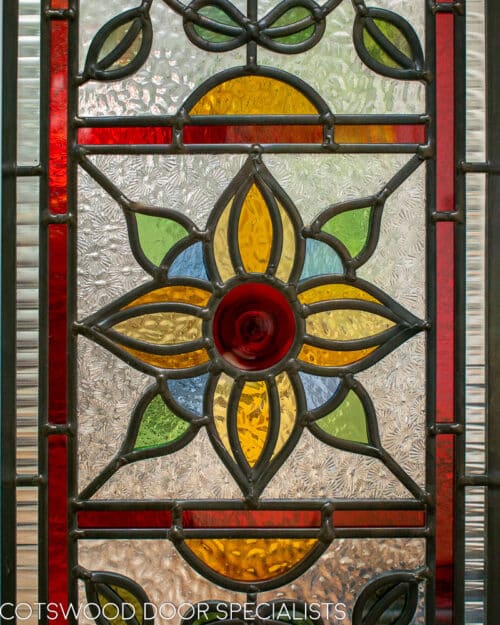 Stained glass Edwardian internal doors. Large pair of white painted wooden internal doors dividing kitchen diner and living room. Door have ornate stained glass with multiple panes. Closeup of stained glass