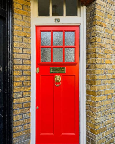 Textured glass 1920s door. 1920s door is painted bright red with brass furniture including a lion knocker. Door is fitted into a north london yellow stock home