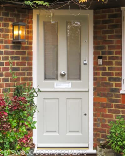 4 panel stable door painted a light grey. Door fitted as a front door. Top opening to allow ventilation but still keep children and animals in or out. Red brickwork surround wooden door. Stain etched door glass