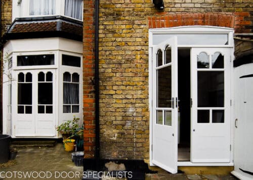 Edwardian french doors painted white. Glass in doors has decorative shapes matching original bay. Doors have a panelled bottom and are fitted into a yellow stock brick london home. Clear double glazed glass. Photo showing orginal edwardian doors and replica new wooden ones