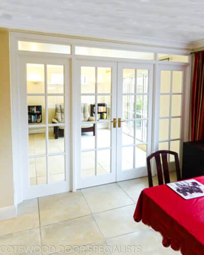 Edwardian room dividing doors. Edwardian doors featuring Georgian style glazing bar dividing each door into 8 lights. Large door frame has fixed glazed side panels and transom. Clear glass to let light though and bright white painted doors
