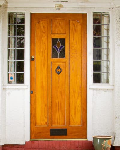 Dutch scroll 1920s door. Solid oak front door fitted with stained glass into a 1920's dutch gabled house. Door has a scrolled head and simple flat panels. Traditional black door furniture