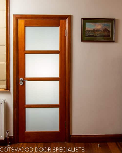 Modernist internal door. Horizontal glazing bars dividing the door into four glazed sections. Elegant modern door and frame in dark wood. White obscured glass fitted to door. Door and frame made of same timber