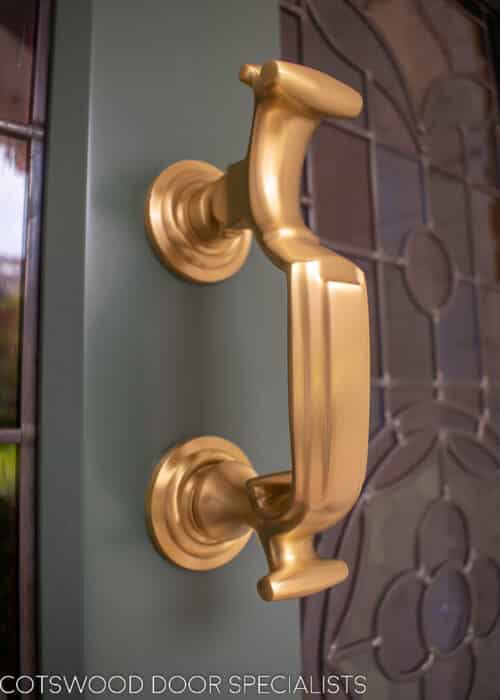Stop chamfered Victorian front door painted green with satin brass door furniture. Stop chamfered mouldings to panels, glass and frame. Panels also have tongue and groove boarding set at an angle. Stained glass ring number and floral design. Closeup of door knocker