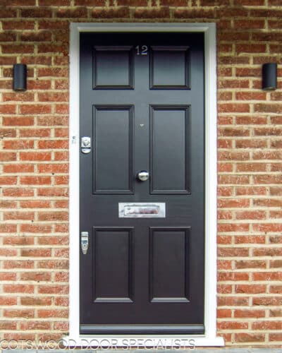 Classic Georgian front door. Smooth stain black painted georgian front door with a white door frame fitted into a red brick london home. Polished chrome door furniture with a letterplate, door knob and locks. Banham locks