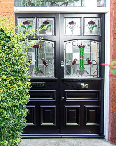 Art Nouveau Double doors. Doors are painted black with chrome door fittings. Recreation of orginal edwardian design- highly decorative. Stained glass with different glass textures incluing reeded glass. Black doors, white frame red brickwork