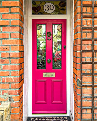 Pink Nouveau Victorian Door fitted into a london home. Antique brass door furniture. Bespoke stained glass with a rennie mackintosh theme. Glass above door with number in stained glass