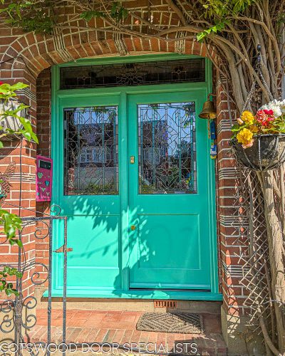 Turquoise green front door. Fitted into a London 1930s brick built house. Beautiful stained glass design incorporating watery tone and flowers and leaves. Painted accoya wood door with durable Teknos paint. Double glazed stained glass. Turquoise paint and polished brass door hardware