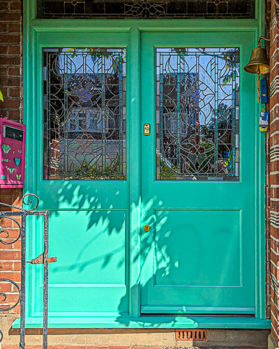 Turquoise green front door. Fitted into a London 1930s brick built house. Beautiful stained glass design incorporating watery tone and flowers and leaves. Painted accoya wood door with durable Teknos paint. Double glazed stained glass. Turquoise paint and polished brass door hardware