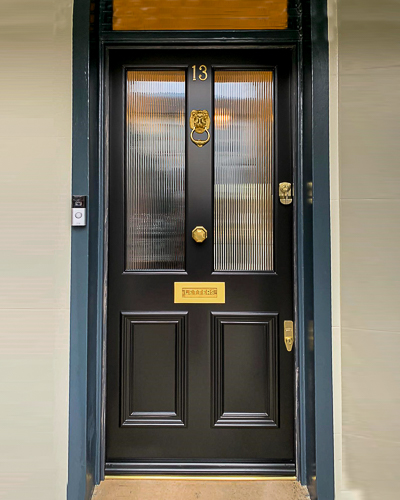 Reeded glass Victorian front door Victorian front door, based upon 4 panels with the top two glazed. The glazed panels have reeded glass, giving a modern classic appearance. Door is painted black with Teknos paint and is made from Accoya wood. Draught proofed and insurance rated high security banham locks fitted in polished brass. Door has a lion door knocker, door knob and also a letterplate with "letters" embossed on it. fitted into a classic london doorway with glazing above the door